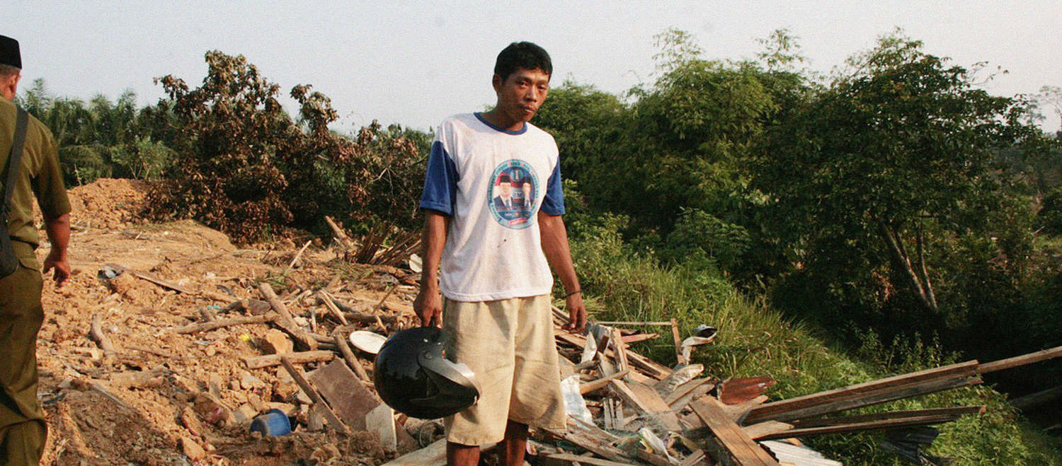 ein Bauer steht vor den Trümmern seines Dorfes