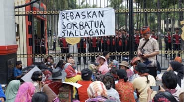 Protest in front of high fence with banner “Free Sorbatua Siallagan”