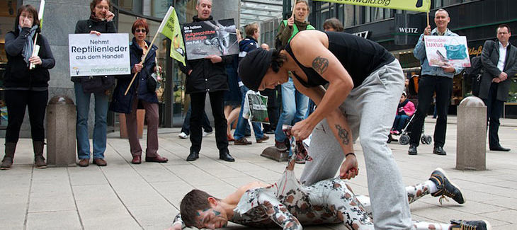 Ein Mensch verkleidet sich als Schlange und wird von einem anderen "gehäutet"