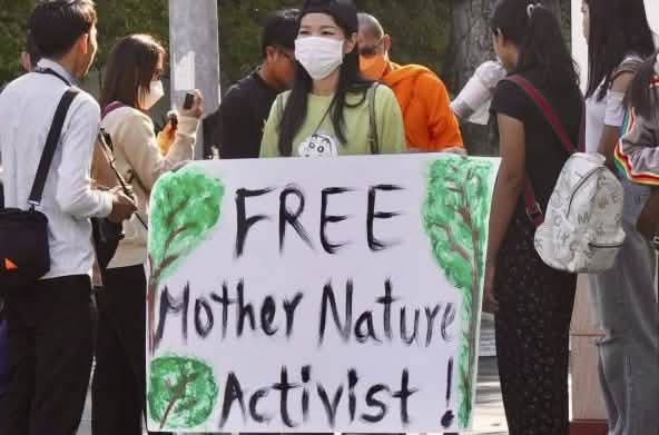 Aktivistin hält großes Plakat in die Kamera mit dem Text „Free Mother Nature Activist!