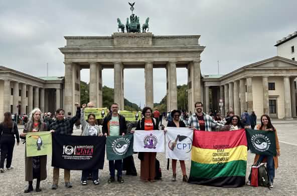 Eine Gruppe von 11 Personen mit Bannern vor dem Brandenburger Tor in Berlin