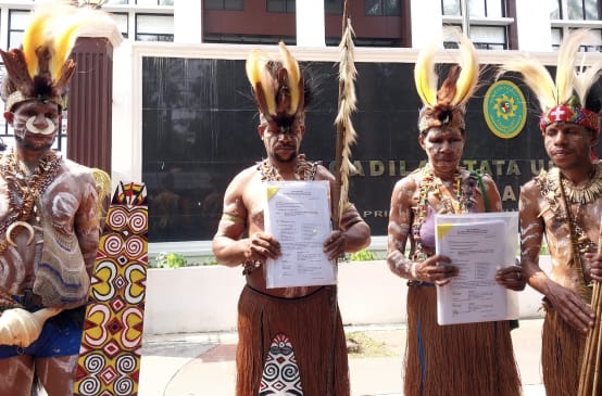 vier Papua in traditioneller Kleidung vor Gerichtsgebäude