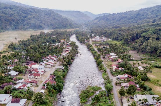 Fluss durch Dorf, im Hintergrund Berge