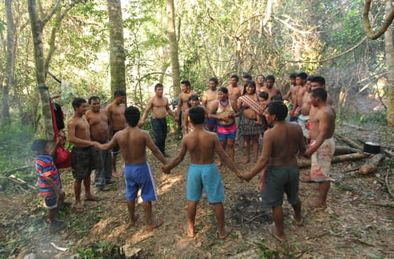 Indigene Ka'apor - Kinder, Frauen und Männer - fassen sich an den Händen und bilden einen Kreis im Regenwald