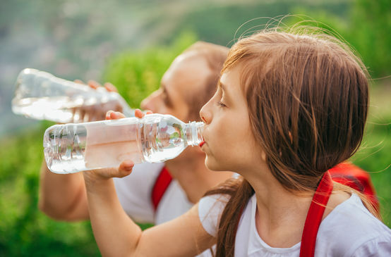 Ein junges Mädchen trinkt Wasser aus einer PET-Einwegflasche