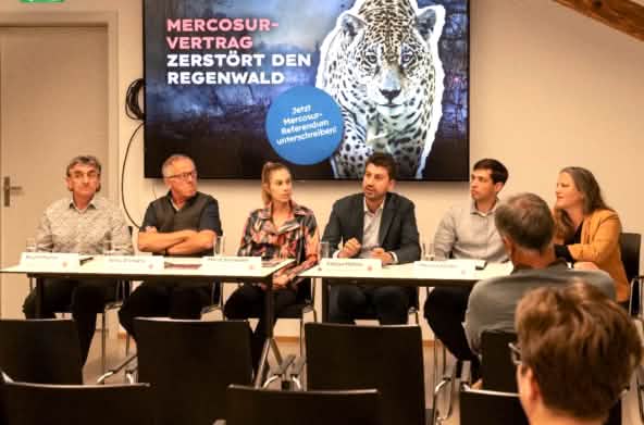 6 Personen bei Pressekonferenz, Banner mit "Mercosur-Vertrag zerstört den Regenwald"