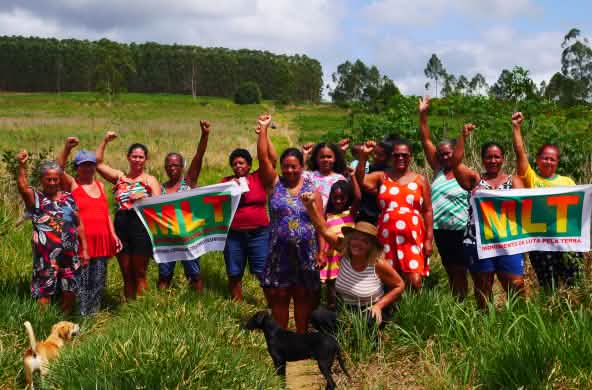 Eine Gruppe von 15 Frauen protestiert mit erhobenen Fäusten und zwei Bannern mit der Aufschrift MLT