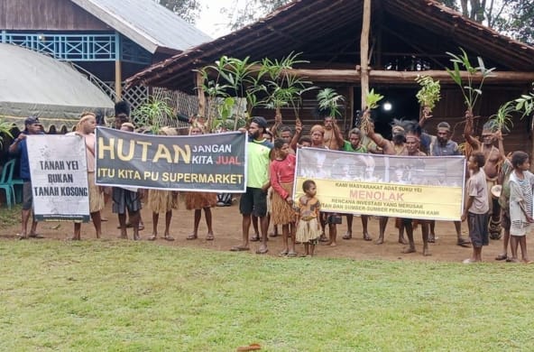 Demo der indigenen Yei mit Bannern vor einem Haus