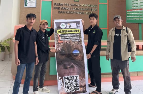 vier Leute mit großem Plakat #SaveRawaTripa in Behörde
