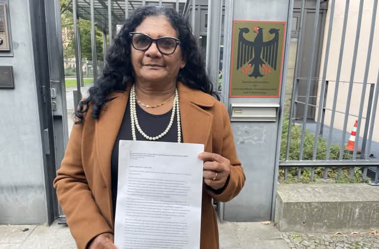 Die Quilombola-Frau Marli Borges mit einem Schreiben vor dem vergitterten Eingang des Bundesentwicklungsministeriums (BMZ)