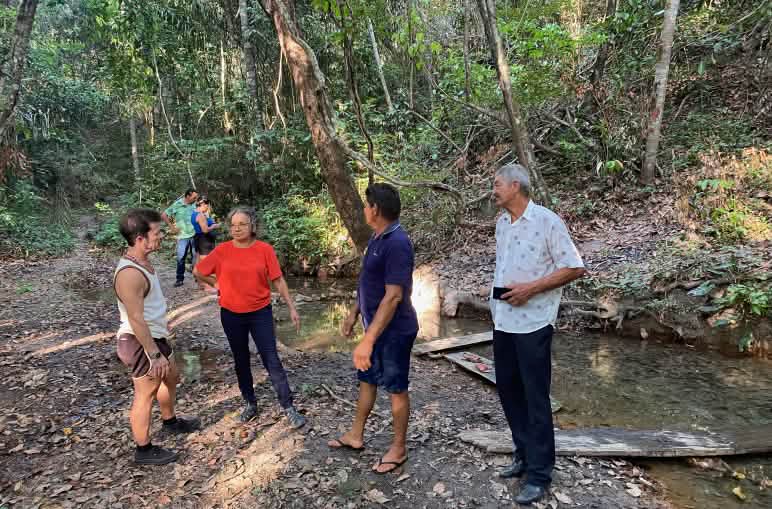 Eine Gruppe von Personen steht an einer Wasserquelle im Regenwald