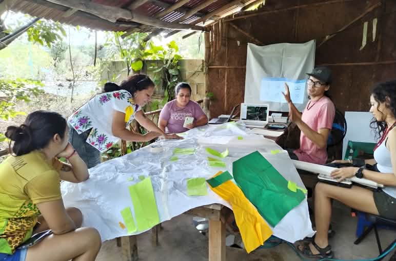 Fünf Personen arbeiten an einem Tisch an Materialien