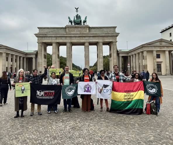 Eine Gruppe von 11 Personen mit Bannern vor dem Brandenburger Tor in Berlin