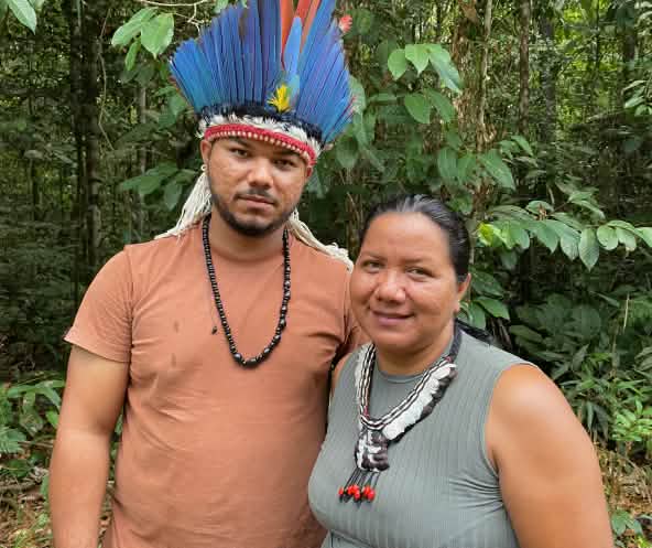 Porträt einer indigenen Frau mit Federhalskette rechts und eines jungen indigenen Mannes mit Federkrone links