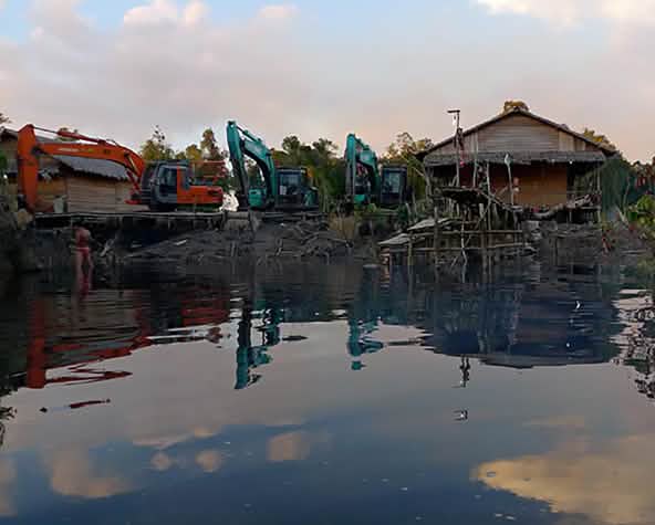 Bagger zerstören Häuser an einem Fluss in Indonesien