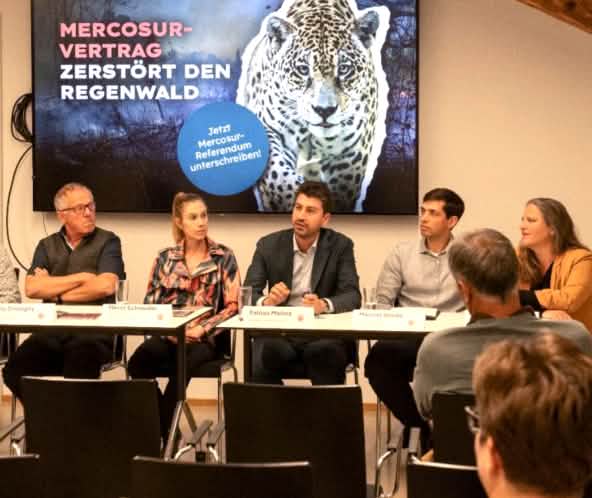 6 Personen bei Pressekonferenz, Banner mit "Mercosur-Vertrag zerstört den Regenwald"