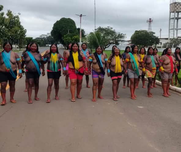 20 indigene Frauen versperren in einer Reihe die Fahrbahn einer Strasse