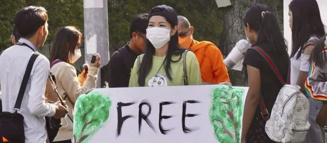 Aktivistin hält großes Plakat in die Kamera mit dem Text „Free Mother Nature Activist!