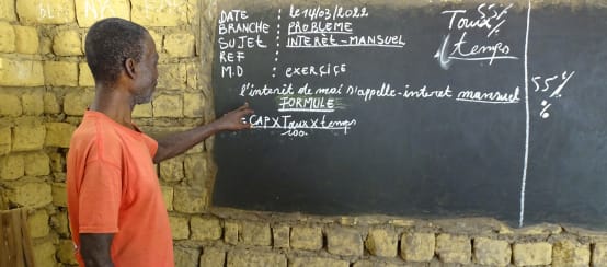 Unterricht im Dorf Bekombo - der Lehrer erklärt monatliche Zinsen (© Bonobo Alive) Lehrer in einer Dorfschule in der Demokratischen Republik Kongo