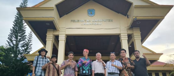 Acht Bürger aus Kinipan vor einem Eingang mit der Aufschrift "Regierung des Bezirks Lamandau"