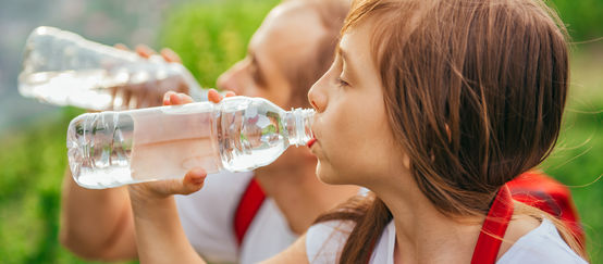 Ein junges Mädchen trinkt Wasser aus einer PET-Einwegflasche