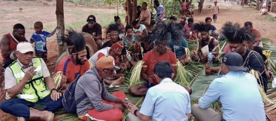 Nach traditionellem Recht der indigenen Marind aus Papua, Indonesien, werden Umweltzerstörung und Abholzung streng bestraft. Ein Ritual bekräftigt das Urteil. (© Pusaka) eine Gruppe Papua sitzt auf Palmblättern