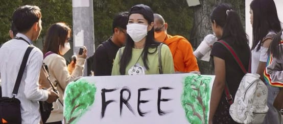 Aktivistin hält großes Plakat in die Kamera mit dem Text „Free Mother Nature Activist!