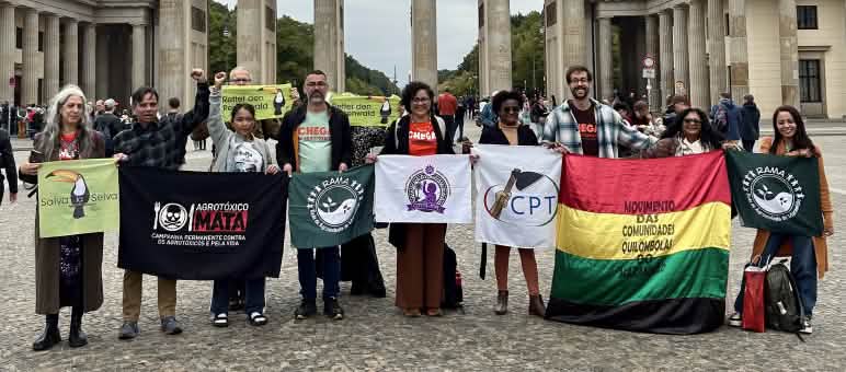 Eine Gruppe von 11 Personen mit Bannern vor dem Brandenburger Tor in Berlin