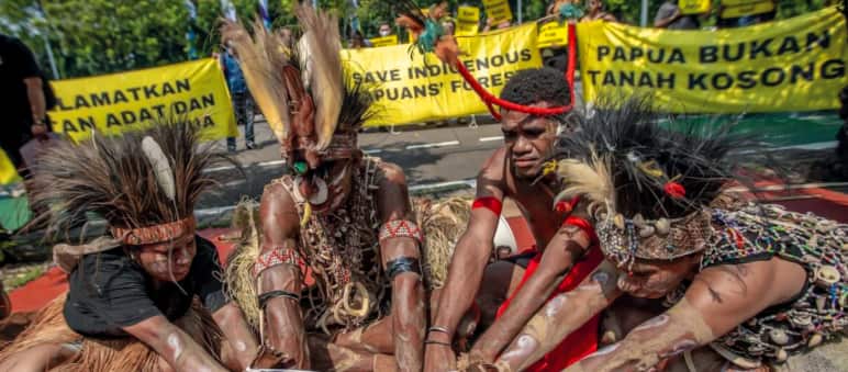 „Auf dieser Erde leben wir!“ Ritual der indigenen Awyu vor dem Obersten Gerichtshof in Jakarta vier Papua mit Federschmuck halten ein Ritual ab. "Papua ist kein leeres Land"