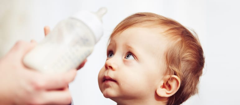 Verbraucherschützer gegen Palmöl Ein Baby wehrt mit sorgenvollem Blick eine ihm hingehaltene Trinkflasche ab