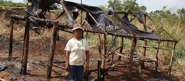 Damiana, ein Guaraní-Kaiowá und religiöse Führerin der Apyka'y, vor einer niedergebrannten Hütte nach Zwangsvertreibungen Guarani-Kaiowá vor zerstörter Hütte
