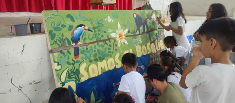 Etwa zehn Kinder malen ein grosses Bild mit Pflanzen und Tieren, das an einer Wand gelehnt steht