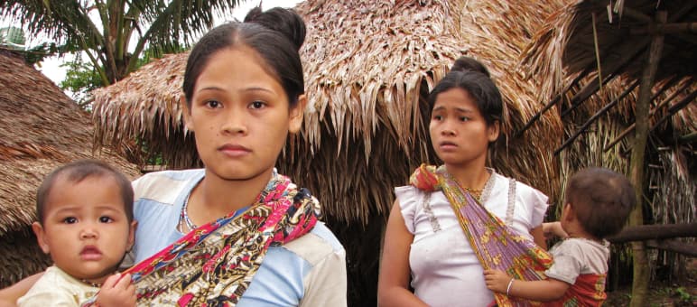 Die indigenen Pala'wan, Ureinwohner der Insel, brauchen zum Überleben ihren Wald, keine Plantagen 2 Frauen mit ihren Kindern vor strohgedeckten Häusern