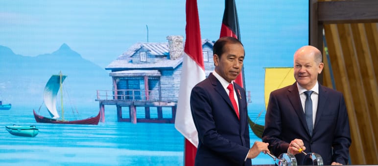 Joko Widodo und Olaf Schulz am Pult vor Bildschirm