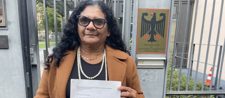 Die Quilombola-Frau Marli Borges mit einem Schreiben vor dem vergitterten Eingang des Bundesentwicklungsministeriums (BMZ)