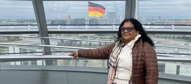 Die Quilombola-Frau Marli Borges in der Glaskuppel des Deutschen Bundestages mit der Bundesflagge im Hintergrund.
