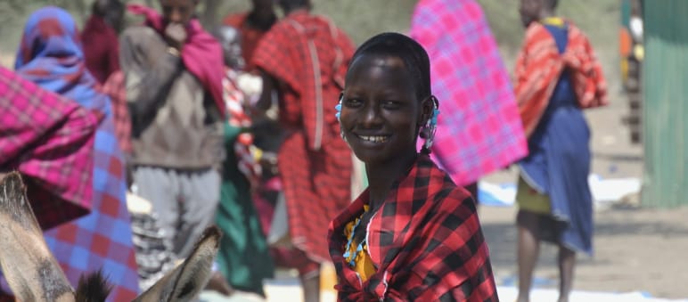 Massai auf einem Markt in der Nähe des Ngorongoro-Kraters Frauen und Männer der Massai in bunten Tüchern auf einem Markt, eine Frau schaut in die Kamera
