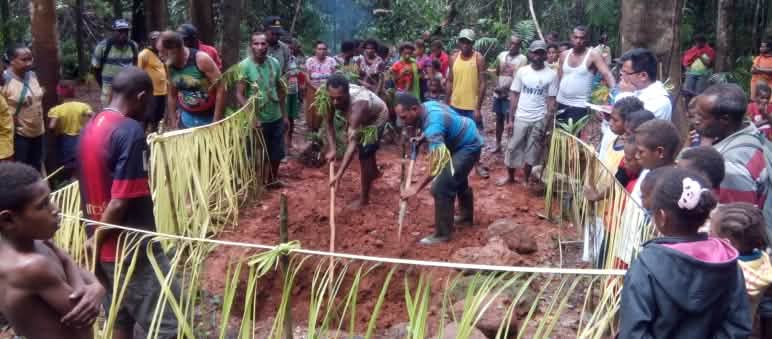Zeremonie für den Schutz des Waldes: Unter Fürbitten graben die Mahuze als heilige Handlung einen Raum in die Erde und pflanzen neue Setzlinge Die Indigenen Papuas stehen im Kreis und beobachten ein Ritual zum Schutz des Territoriums