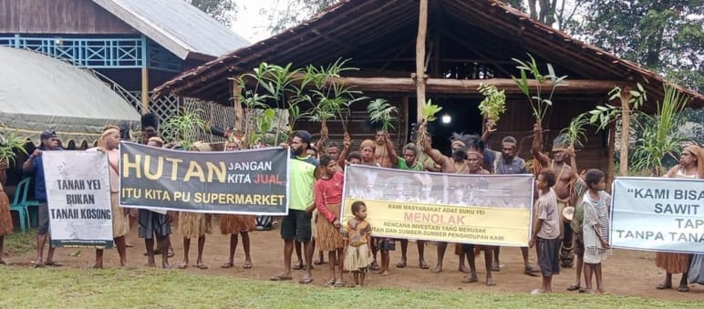 Demo der indigenen Yei mit Bannern vor einem Haus
