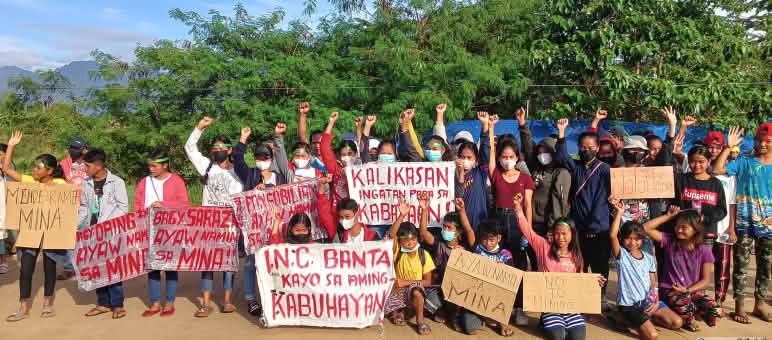 Junge Indigene demonstrieren, halten Plakate und strecken Arme und Fäuste hoch