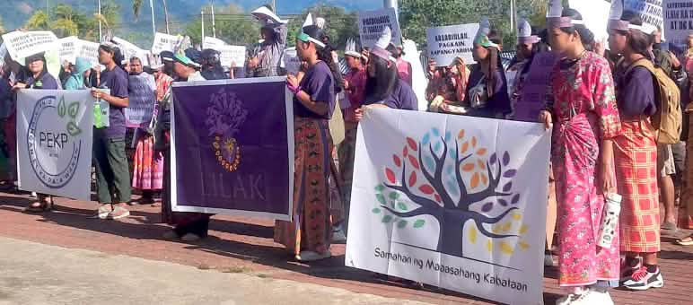 Versammlung von Frauen und Jugendlichen in traditioneller Kleidung mit bunten Plakaten gegen den Bergbau