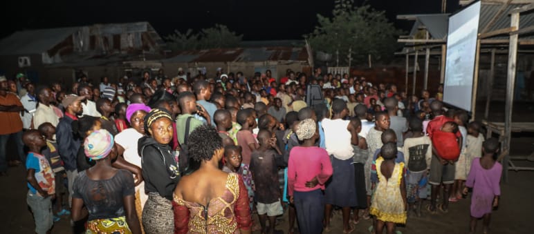 Auf einer großen Leinwand wird der Film "La malédiction du pétrole au Nigeria" gezeigt Filmvorführung Fluch des Erdöls im Dorf Vitshumbi (Virunga),