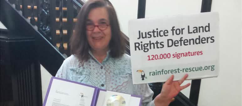 Rettet den Regenwald übergibt 120.000 Unterschriften zur Unterstützung der Landrechtskämpfer in SIerra Leone. Eine Aktivistin von Rettet den Regenwald hält in der Botschaft von Sierra Leone Petition und Übergabeplakat in die Höhe.