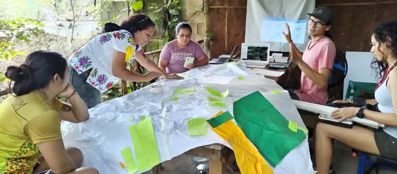 Fünf Personen arbeiten an einem Tisch an Materialien