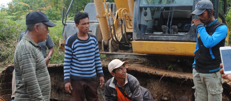 „Was macht ihr hier?“, fragt Wardian (links) die Arbeiter. „Ihr könnt doch nicht einfach die Bäume ausreißen. Das ist mein Land!“ Wardian steht vor einem Bulldozer und diskutiert mit den Arbeitern