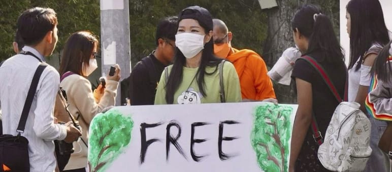 Aktivistin hält großes Plakat in die Kamera mit dem Text „Free Mother Nature Activist!