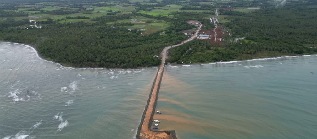 Ein brauner Schiffsanlegedamm führt von der Nickelmine im Regenwald ins Meer hinaus. Luftaufnahme
