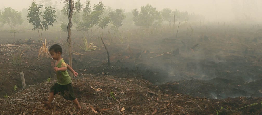 Kind läuft über glimmenden Torf in Katingan auf Borneo