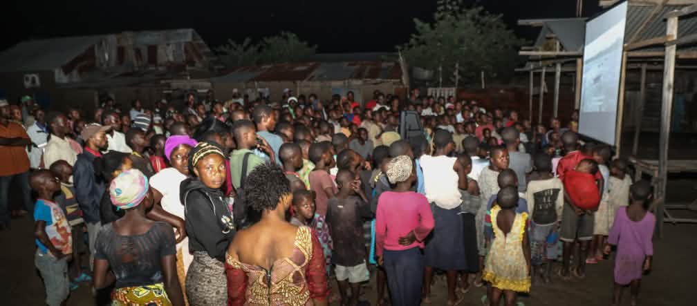 Auf einer großen Leinwand wird der Film "La malédiction du pétrole au Nigeria" gezeigt Filmvorführung Fluch des Erdöls im Dorf Vitshumbi (Virunga),