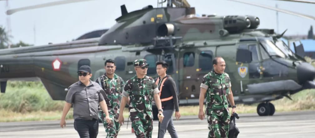 Vor einem Hubschrauber gehen drei Soldaten und zwei Zivilisten
